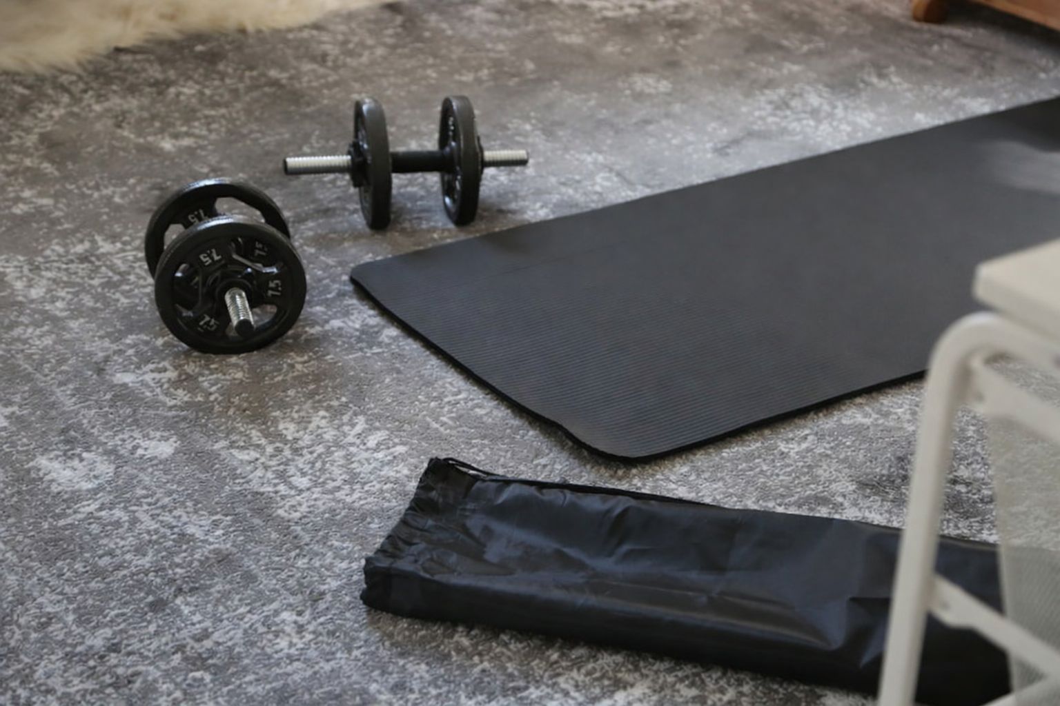 Hantlar och en yogamatta på golvet för ett hemmagym.